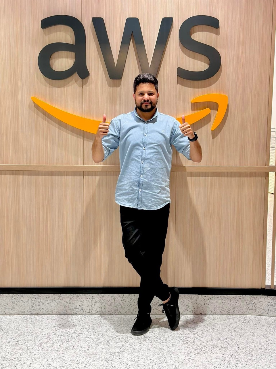 Abid Jamil standing in front of an AWS logo
