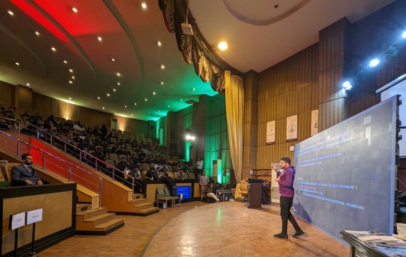 Abid Jamil explaining a code slide on stage at DevFest Lahore 2022