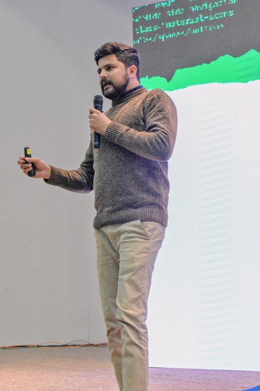 Abid Jamil speaking with a microphone and presentation remote