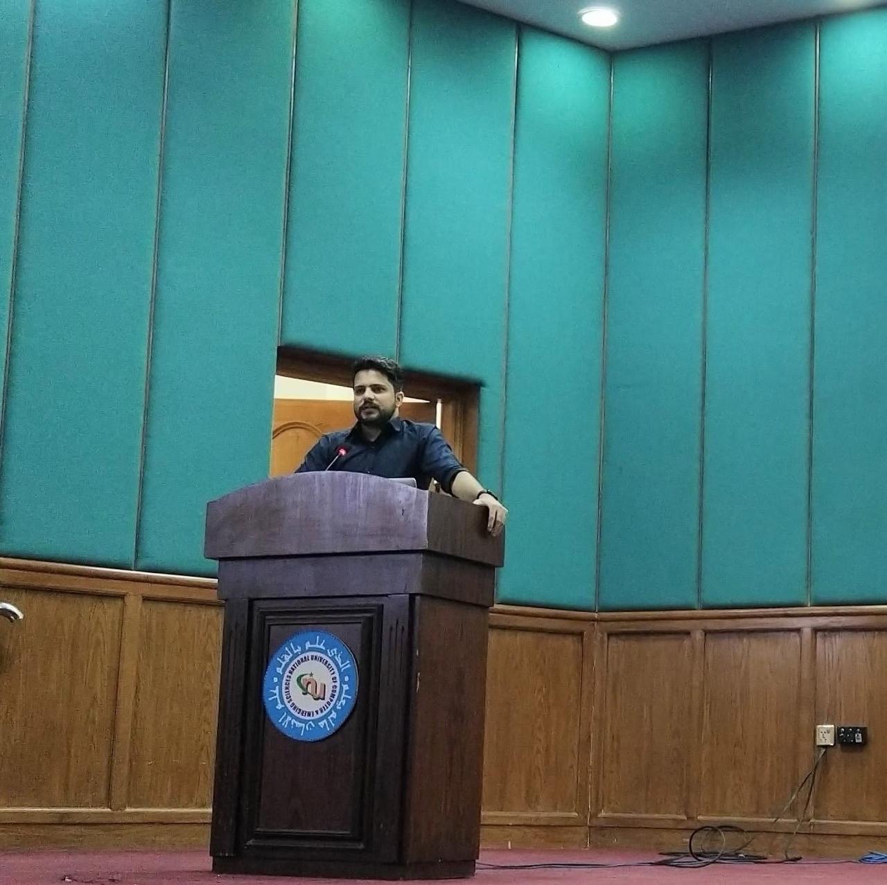 Abid Jamil speaking at a university lectern